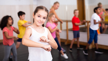 Portrait of emotional girl doing dance workout during group class in studio
