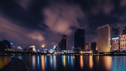 Big city in the night life with reflection of water wave. Long exposure Technics. Panorama of landscape.Town and urban concept. Landscape and attraction theme.
