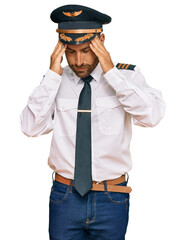 Handsome man with beard wearing airplane pilot uniform with hand on head for pain in head because stress. suffering migraine. © Krakenimages.com
