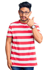 Handsome latin american young man wearing casual clothes and glasses pointing with hand finger to face and nose, smiling cheerful. beauty concept