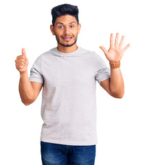 Handsome latin american young man wearing casual tshirt showing and pointing up with fingers number six while smiling confident and happy.