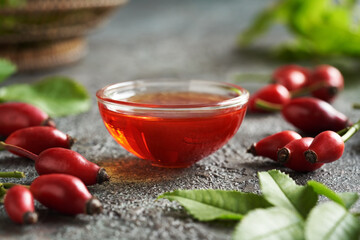 Rose hip seed oil in a bowl with fresh rose hips