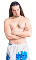 Fototapeta premium Young adult man with long hair wearing swimwear shirtless skeptic and nervous, disapproving expression on face with crossed arms. negative person.