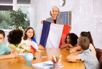at evening geography lesson, elderly teacher tells attentive students about France