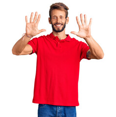 Naklejka premium Handsome blond man with beard wearing casual clothes showing and pointing up with fingers number ten while smiling confident and happy.