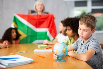 in geography lesson, pupils carefully listen to woman teacher who talks about South Africa