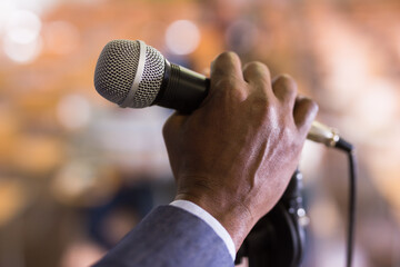 Close up of male hand holding microphone at conference hall