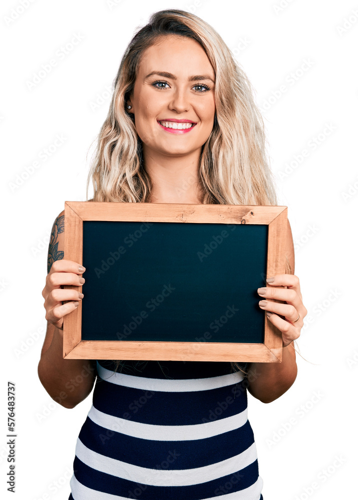 Poster Young blonde woman holding blackboard smiling with a happy and cool smile on face. showing teeth.