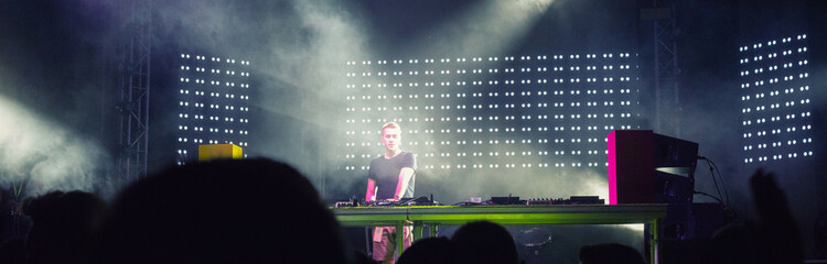 Dj playing techno music on the concert stage at summer night