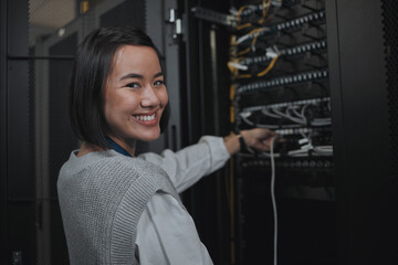Asian woman, portrait smile and technician by server for cabling, networking or system maintenance...