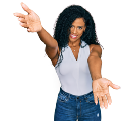 Middle age african american woman wearing casual style with sleeveless shirt looking at the camera smiling with open arms for hug. cheerful expression embracing happiness.