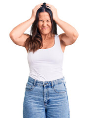 Young beautiful brunette woman wearing casual sleeveless t-shirt suffering from headache desperate and stressed because pain and migraine. hands on head.