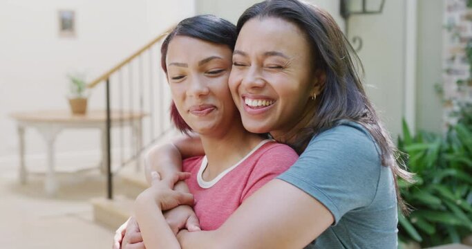 Portrait of happy biracial sisters embracing and smiling in garden, in slow motion