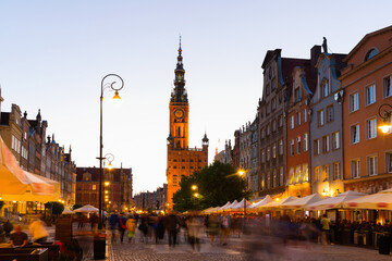 Naklejka premium Illuminated streets of Gdansk with spire of Main Town Hall in twilight, Poland.