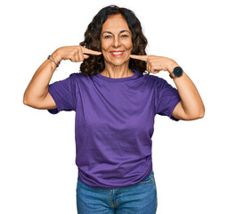 Middle age hispanic woman wearing casual clothes smiling cheerful showing and pointing with fingers teeth and mouth. dental health concept.