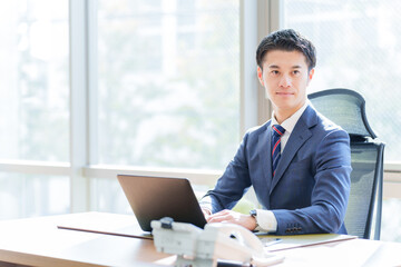 Fototapeta premium オフィスでパソコンを使うビジネスマン