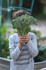 Young boy holding up broccoli 