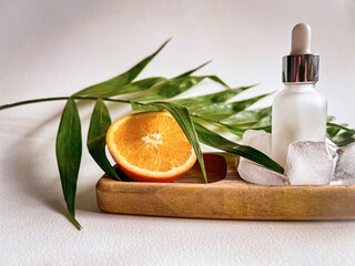 spa still life. Mucin Serum. dropper with orange, ice, and tropical leaves. 