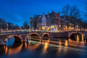 Fototapeta premium Evening panoramic view of the famous historic center with lights, bridges, canals and traditional Dutch houses in Amsterdam, Netherlands