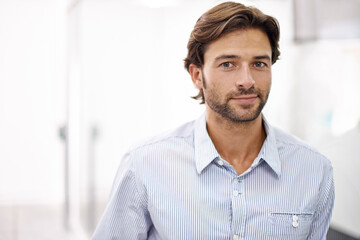 Obraz premium Hes a confident young businessman. Portrait of a handsome young businessman standing in his office.
