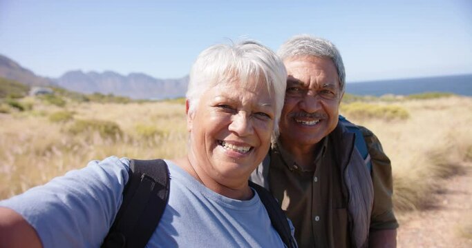 Portrait of happy senior biracial couple in mountains embracing, in slow motion