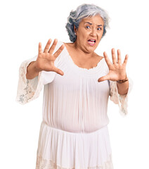 Senior woman with gray hair wearing bohemian style afraid and terrified with fear expression stop gesture with hands, shouting in shock. panic concept.