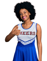 Young african american woman wearing cheerleader uniform doing happy thumbs up gesture with hand. approving expression looking at the camera showing success.