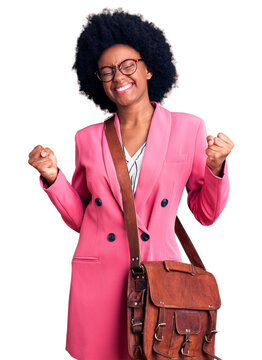 Young african american woman wearing business clothes and leather bag very happy and excited doing winner gesture with arms raised, smiling and screaming for success. celebration concept.