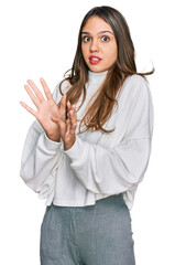 Young brunette woman wearing casual turtleneck sweater afraid and terrified with fear expression stop gesture with hands, shouting in shock. panic concept.