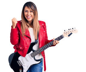 Fototapeta premium Young beautiful woman playing electric guitar screaming proud, celebrating victory and success very excited with raised arms