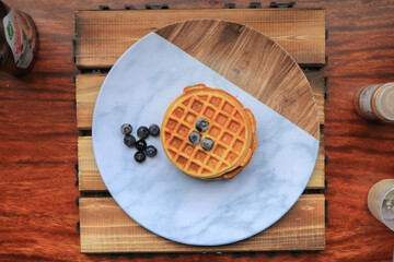 waffles with blueberries, cinnamon, and flour, marble plate and wooden background