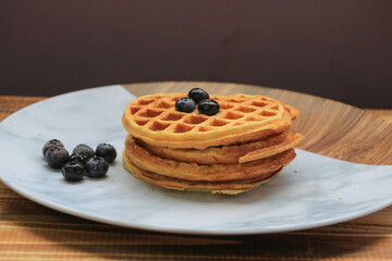 waffles with blueberries, cinnamon, and flour, marble plate and wooden background