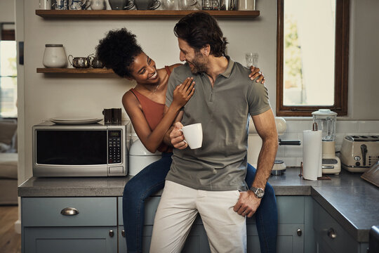 Theyre each others happiness. Cropped shot of an affectionate young couple smiling at each other while spending quality time in their kitchen at home.