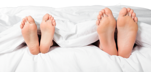 Beautiful feet of a young couple lying in bed close up.