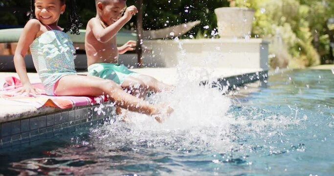 Happy african american siblings playing at pool, in slow motion
