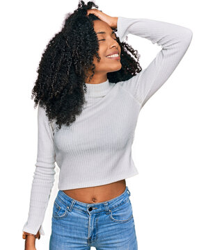 Young african american girl wearing casual clothes smiling confident touching hair with hand up gesture, posing attractive and fashionable