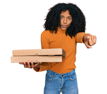 Young african american girl holding delivery pizza box pointing with finger to the camera and to you, confident gesture looking serious