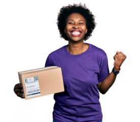 African american woman with afro hair holding delivery package screaming proud, celebrating victory and success very excited with raised arm