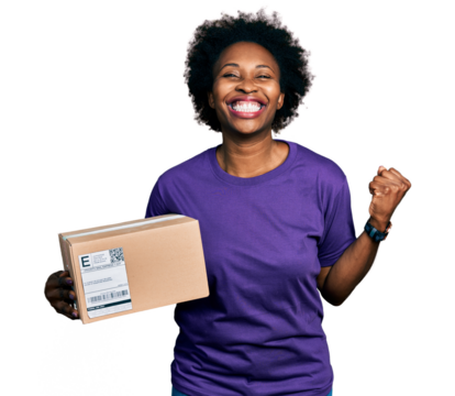 African american woman with afro hair holding delivery package screaming proud, celebrating victory and success very excited with raised arm