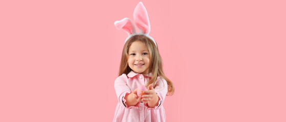Cute girl with bunny ears and Easter egg on pink background