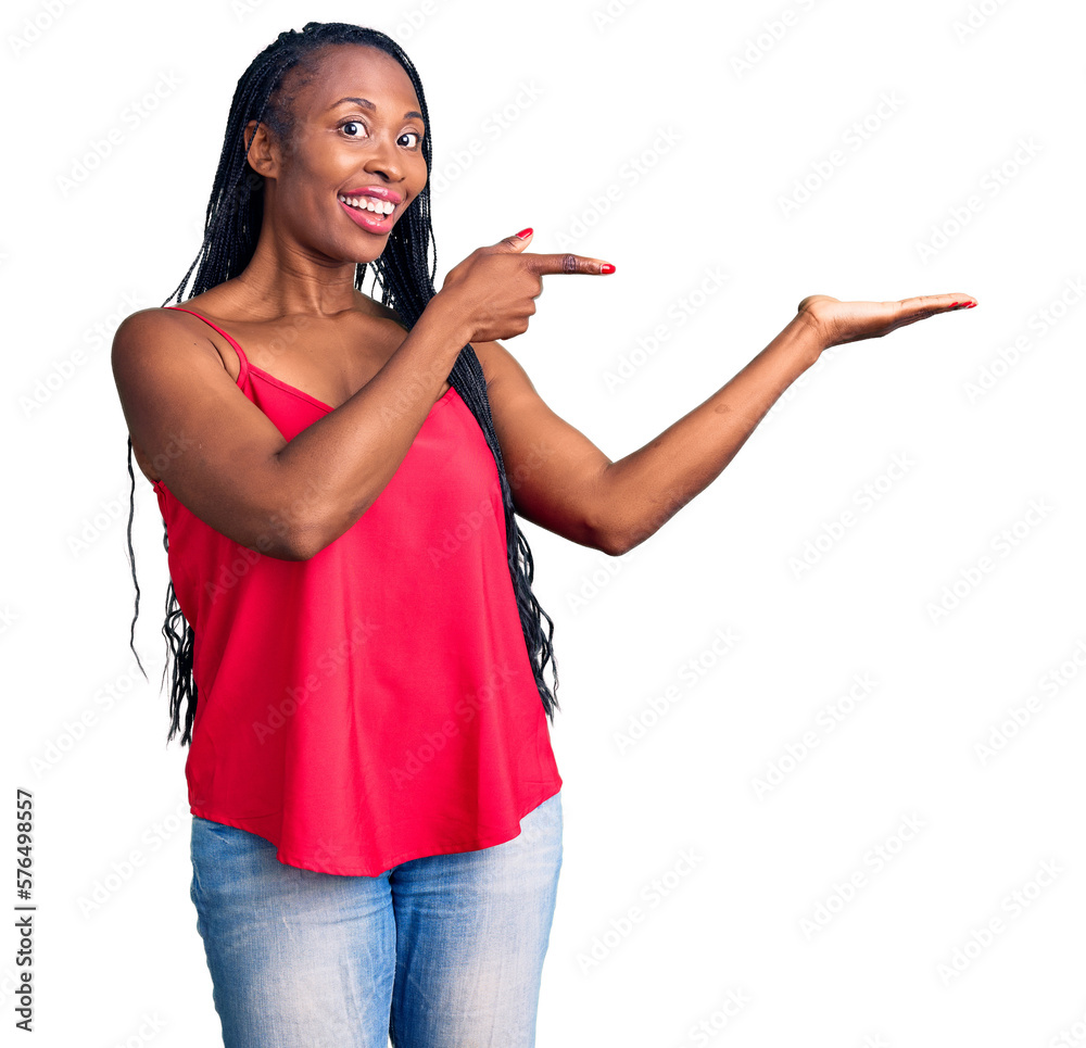 Wall mural young african american woman wearing casual clothes amazed and smiling to the camera while presentin