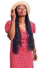 Young african american woman wearing summer hat doing italian gesture with hand and fingers confident expression