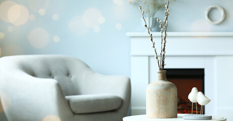 Vase with willow branches and decor on table in living room