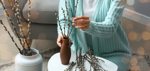 Woman putting willow branches into vase on table at home © Pixel-Shot
