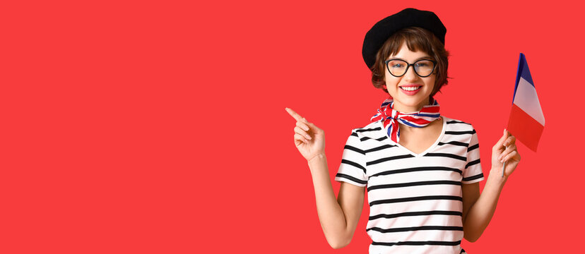 Young woman with flag of France pointing at something on red background with space for text
