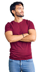 Handsome hispanic man wearing casual clothes looking to the side with arms crossed convinced and confident