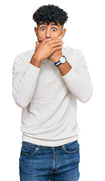 Young arab man wearing casual winter sweater shocked covering mouth with hands for mistake. secret concept.