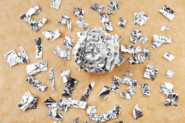 Crumpled ball and pieces of aluminium foil on color background