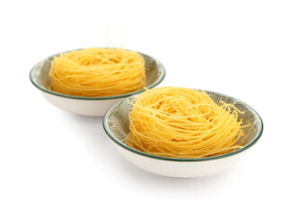 Bowls of raw pasta nests on white background