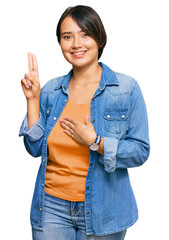 Young beautiful hispanic woman with short hair wearing casual denim jacket smiling swearing with...